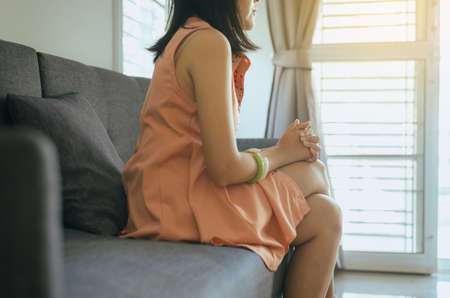 Unexpected pregnancy concept,Asian woman sitting at house,Female feeling unhappy and confused problem alone,Selective focus handsの写真素材