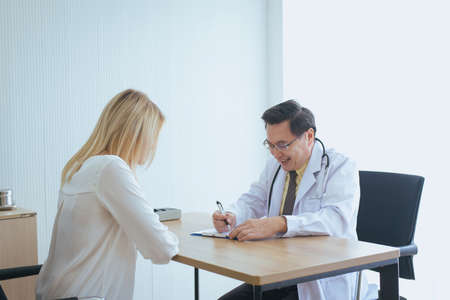 Man doctor examining asian woman patient and follow up treatment at hospitalの写真素材