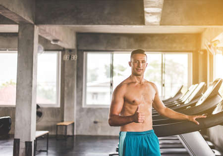 Fit man standing and thumb up relax after the training session in gym,Concept healthy and...