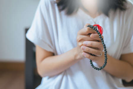 Woman with hand in praying position,Female prayer hands with beads cross the hands,Close upの写真素材