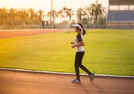 Young beautiful asian woman runner running on track during sunsetの写真素材
