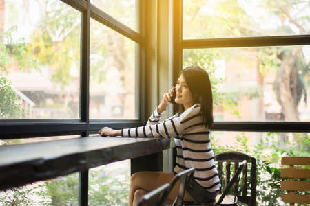 Asian beautiful young woman using cell phone in modern restaurant,Happy and charming,Positive thinkingの写真素材