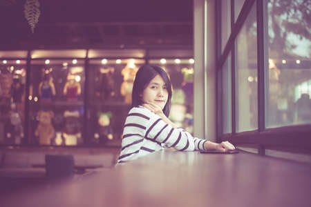 Portrait of beautiful asian woman smiling and looking camera in coffee shop cafe,Happy and fresh with positive thinking,Vintage color tonedの写真素材