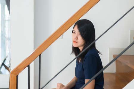 Asian woman sitting on stairs with depression of lonely have a headache,Mental disorder health care conceptの写真素材