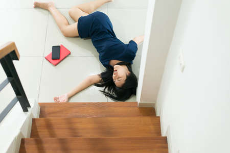 Asian woman falling down of staircase and having injured at home