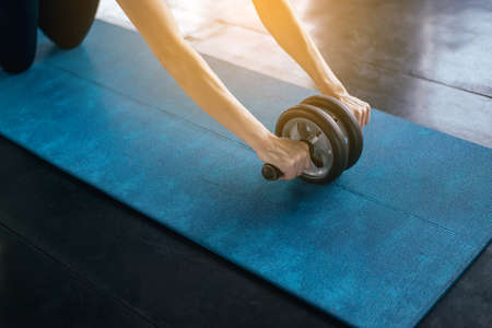 Sporty asian female doing workout and exercise with roller wheel on yaga mat,Close upの写真素材