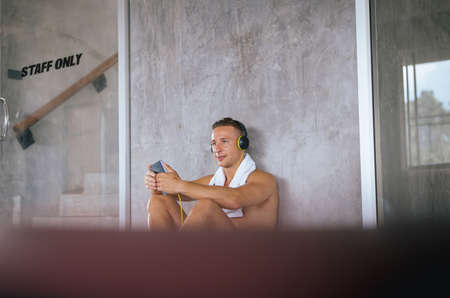 Concept healthy and lifestyle,Sport man using headphone and listening to music while sitting with...