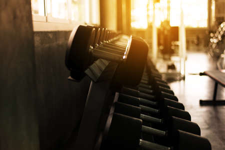 Picture of blured dumbbells set at the gym center,Equipment weight training on rack,Dark toned close upの写真素材