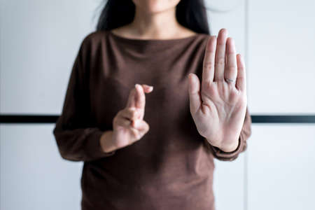 Woman showing hand stop and blured lie crossing fingers telling liar,April Fools' Day concept