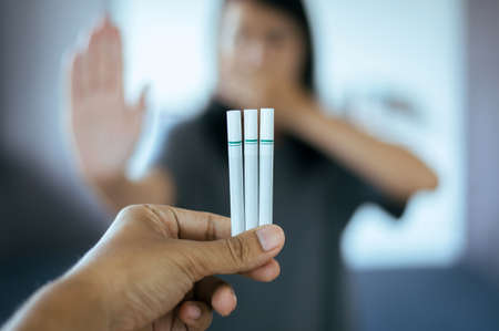 Picture of cigarette with blurred woman showing hands stop,Concept no smoking day world quitting...