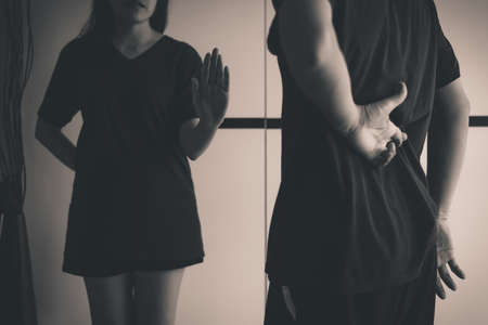 Woman showing hand stop to liar man with hand crossing fingers behind back telling lie and cheating,April Fools' Day concept,Black and white tonedの写真素材