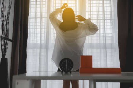 Pictured of refreshing asian women stretch lazy in bedroom after waking up at 6 o'clock in the...