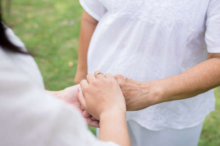 Hand of asian women holding elderly hands while walking at park,Senior taking care conceptの写真素材