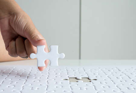 Hands putting piece to white jigsaw puzzle,Concept partnership business successful teamwork,Close up