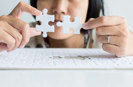 Hands asian woman with jigsaw puzzle white color,Puzzle pieces grid,Close upの写真素材