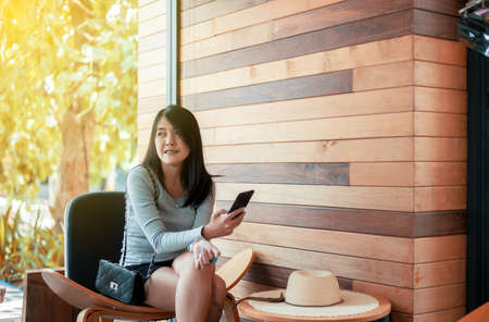 Beautiful asian woman using internet with her smartphone in hotel,Happy and smiling,Positive thinking,Copy space for textの写真素材