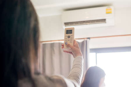 Woman hands using on a remote control to activating air conditioning system