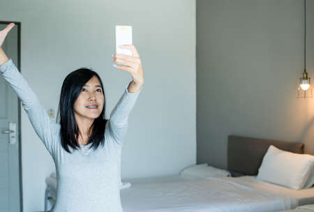 Asian female hand using on a remote control to activating air conditioning system,Happy and smilingの写真素材