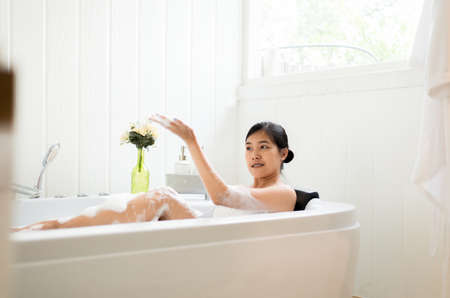 Beautiful asian woman relaxing in bubble bathtub in the morning,Female lying body in waterの写真素材
