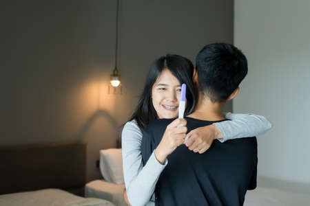 Happy asian couple lover smiling after testing pregnancy test in bedroom,Copy space for textの写真素材