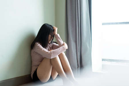 Mental disorder health care concept,Asian female feeling depression of lonely have a headache while sitting in roomの写真素材