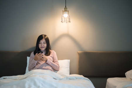 Beautiful asian female using cell phone in bedroom at night,Eye diseases and eyes disorders concept