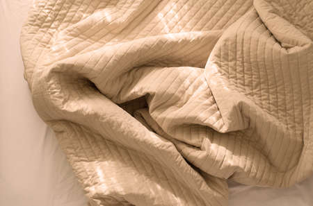 Crumpled blanket with sunlight on bed after wake up in the morning,Brown color tonedの写真素材