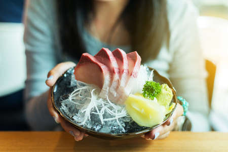 Closeup of hand woman holding Tuna Hamachi,Sushi set Salmon Japanese food in traditional Japan