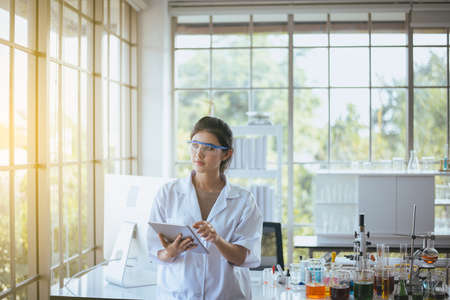 Beautiful young asian woman chemist research new project with tablet at laboratory