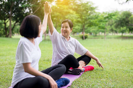 Healthy and lifestyle concept,Asian women raise up hands and relax at park in the morning together,Happy and smiling,Positive thinkingの写真素材