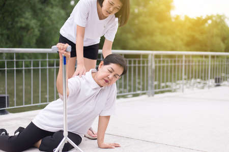 Senior asian woman with faint sitting on floor after falling down,female take care and supportの写真素材