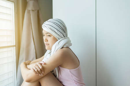 Young asian women with disease cancer is sitting in bedroomの写真素材