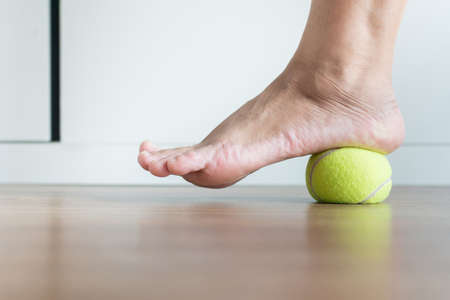 Women massage with tennis ball to her foot in bedroomの写真素材