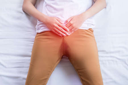 Hands woman holding her crotch and lying on bed, Urinary stain incontinence