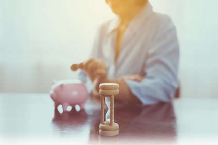 Blurred senior hands putting coin to piggy bank for retirement,Saving money concept, Saving money concept, Sandglassの写真素材