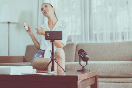 Beautiful woman blogger review and demonstration cosmetics product on cell phone camera screenの写真素材