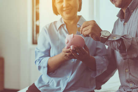 Senior asian couple hands putting coin to piggy bank for retirement together, Saving money concept