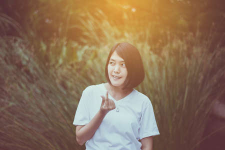 Portrait of asian woman short hair standing and showing hands love shape at park, Happy and smile faceの写真素材