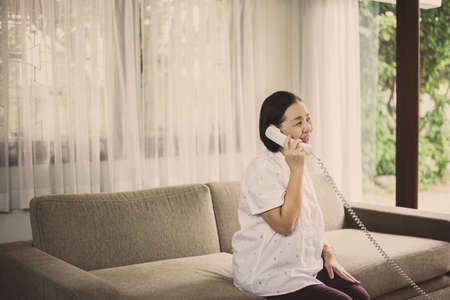 Happy senior asian woman talking on the phone at home