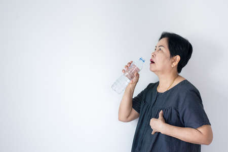 Senior asian woman having or symptomatic reflux acids,Gastroesophageal reflux disease,Drinking...