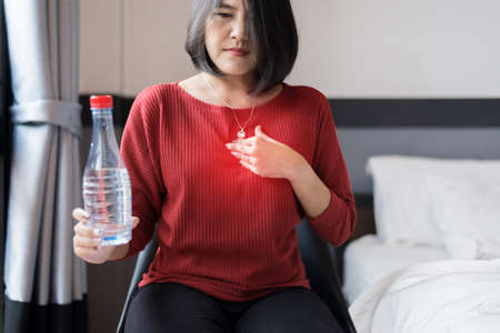 Asian woman having or symptomatic reflux acids,Gastroesophageal reflux disease,Because the esophageal sphincter that separates the esophagus and stomach dysfunctionの写真素材