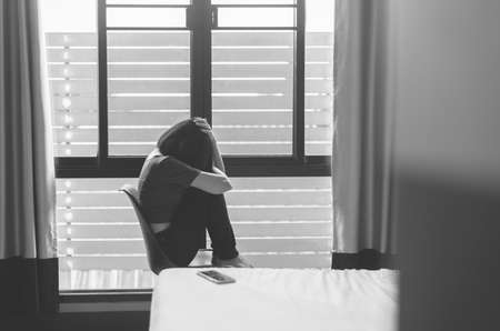 Woman disappointed in life while sitting on chair in bedroom,Suicide prevention,Positive attitude and open mind,Mental health care concept,Black and white tonedの写真素材
