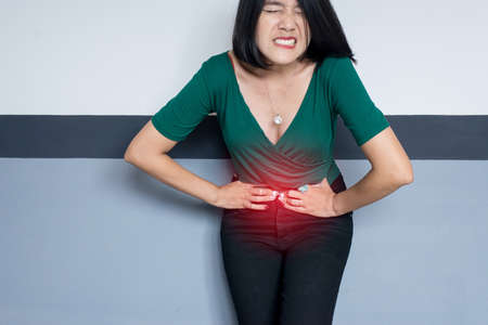 Woman having painful stomach ache at home,Female suffering from abdominal pain, Period cramps, Hands...