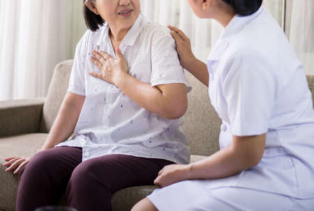 Elderly asian woman having chest pain suffering from heart attack,Nurse take care and supportの写真素材