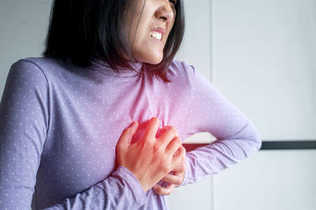 Asian woman with strong chest pain and hands touching her chest,Heart attack symptomの写真素材