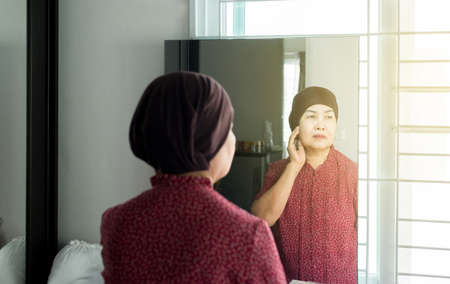 Chemotherapy concept,Senior asian woman with disease cancer standing and looking something in her bedroom,Elderly female feeling depressed and upsetの写真素材