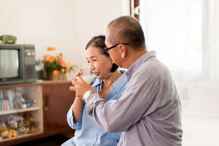 Asian elderly couple drinking milk for breakfast at home, Retirement senior lifestyle living conceptの写真素材