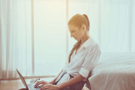Hand woman typing keyboard and using laptop in bedroom, Online shopping conceptの写真素材