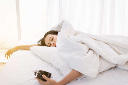 Bored young asian woman hates getting stressed waking up early on bed, Alarm clock