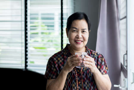 Senior asian woman hands holding a glass of water ,Happy and smiling, Elderly healthy and lifestyle conceptの写真素材